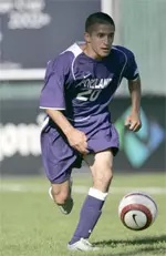 Matt Dallman driving forward with the ball in the purple of the Portland Pilots