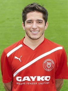 Matt Dallman smiling in the red Sportfreunde Siegen shirt on portrait day